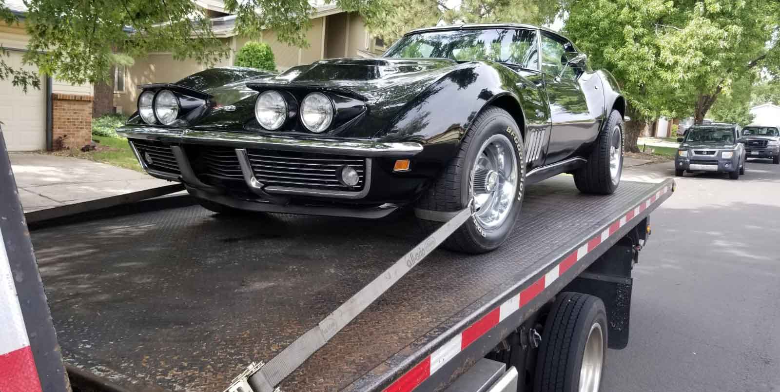 Black Corvette Stingray on our flatbed tow truck in a Denver neighborhood