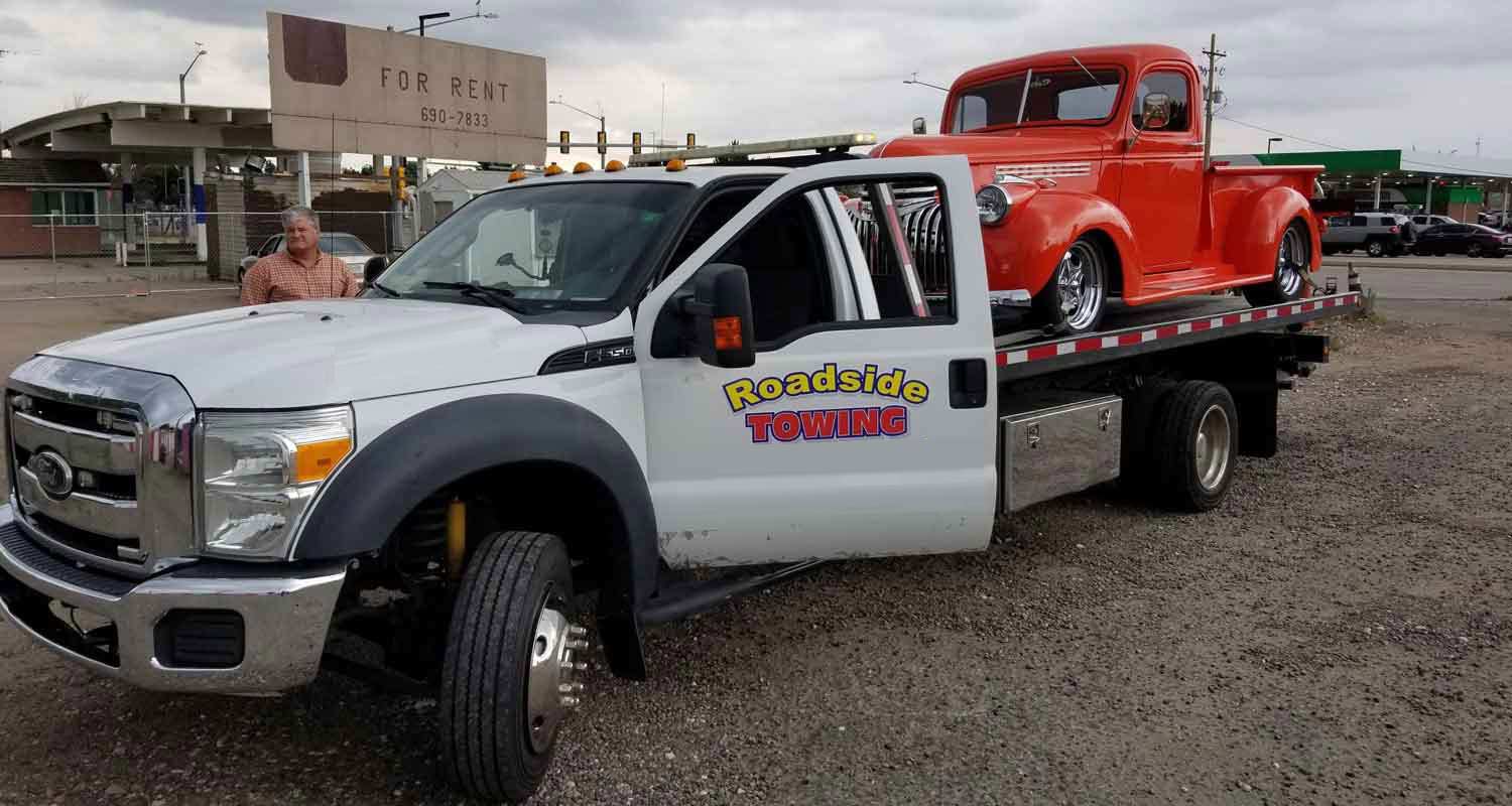 Our branded tow truck hauling a classic cherry-red vintage pickup with care